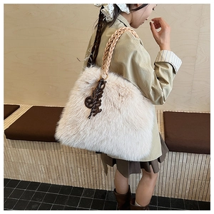 Detail of plush cream tote bag with thick woven rope handle and brown resin pendant