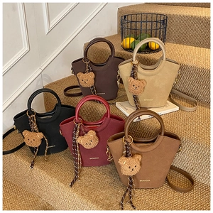 Détail de sacs seaux vintage en cinq couleurs avec breloques d'ours et rubans élégants