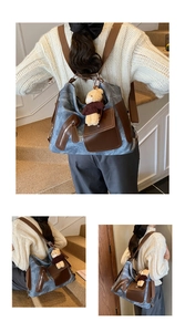 Detail of blue denim canvas tote bag with leather trim and brown teddy bear charm accessory