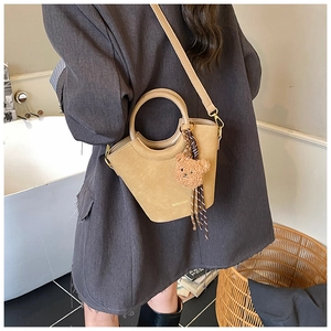 Détail du sac seau marron chameau avec poignée ronde et accessoire de charme d'ours mignon