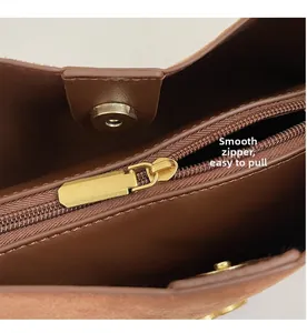 Detail of brown suede bag showing golden zipper pocket and magnetic closure