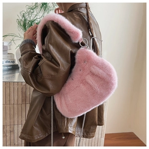 Détail d'un sac selle en peluche rose avec bandoulière chaîne argentée sur modèle