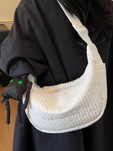 White quilted crescent shoulder bag with CasorKvor logo and black cartoon plush charm