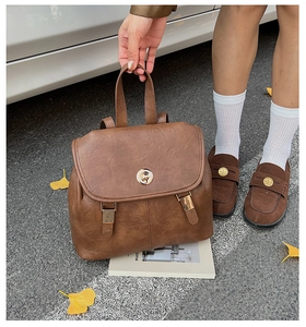 Detail of vintage brown leather backpack with golden rotary lock and retro metal buckles