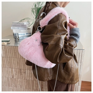 Sac à bandoulière en peluche rose avec étoile en métal et chaîne porté par un mannequin