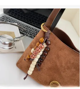 Close-up of brown faux suede shoulder bag featuring a vintage multicolored beaded tassel charm