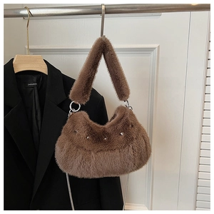 Gros plan sur un sac selle en peluche marron avec clous et bandoulière en chaîne
