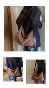 Brown suede hobo bag with wide black leather strap shown on shoulder for daily commute