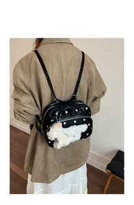 Polished black backpack with white polka dots and cute plush puppy keychain on model back