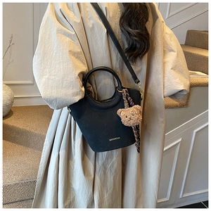 Détail du sac seau vintage noir avec breloque ours en peluche et décor de foulard en soie