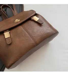 Detail of vintage brown leather backpack showing textured material and gold metal clasp lock