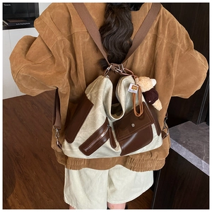 Detail of canvas hobo bag with leather trim and cute bear charm shown on a model