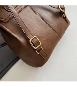 Detail view of brown lychee-textured leather backpack with gold metal buckle