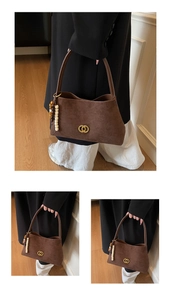 Detail of vintage brown suede underarm bag featuring a gold double ring buckle and beaded charm