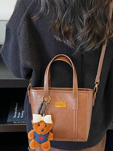 Brown faux leather tote bag with gold logo and cute bear charm for office commute