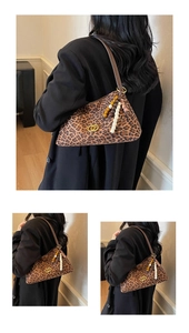 Detail of leopard print underarm bag with gold ring hardware and vintage beaded charm