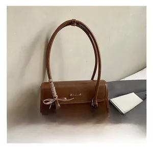 Détail du sac sous le bras en cuir marron avec ruban écossais et breloque en peluche biscuit
