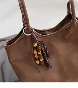 Détail d'un charme en perles de bois vintage avec anneau sur un sac cabas en cuir marron