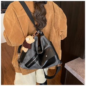 Detail of grey canvas patchwork tote bag with leather flap pocket and plush bear charm