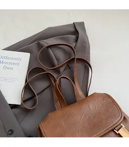 Close-up of brown vintage backpack with gold circular twist lock and faux leather texture