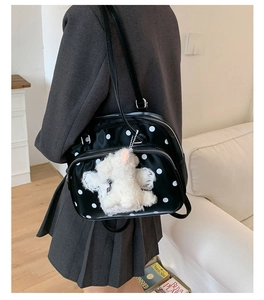 Detailed back view of a black polka dot backpack with a cute white plush bear pendant
