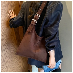 Detail of adjustable silver buckles on a brown suede shoulder bag strap for women