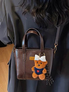 Deep brown faux leather tote bag with golden logo plate and cute plush bear charm