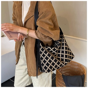 Side view of suede shoulder bag with geometric grid pattern and wide black strap