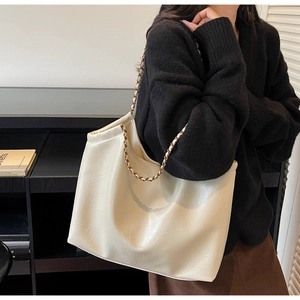 Detail of cream white tote bag featuring woven chain strap and textured faux leather finish
