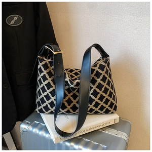 Detail of jacquard weave geometric pattern and black leather strap on a shoulder bag