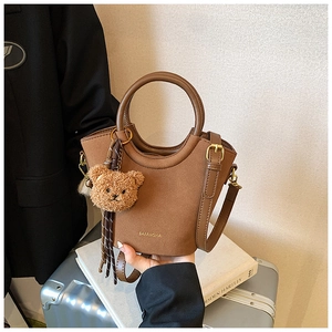 Détail du sac seau vintage marron avec breloque ours et poignées renforcées élégantes