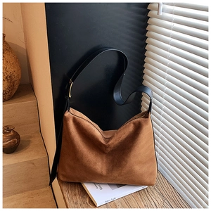 Detailed view of caramel suede tote bag with black leather strap and gold buckle