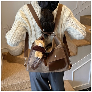 Detailed view of vintage brown tote backpack with cute bear pendant and side zipper details