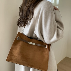 Close-up of brown suede tote bag featuring a silver twist lock and leather strap