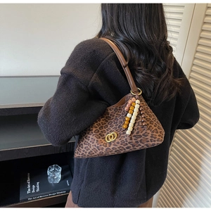 Detail of leopard print underarm bag with gold buckle and colorful beaded tassel charm