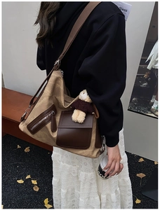 Detail of khaki canvas tote bag with brown leather pockets and a small plush bear charm