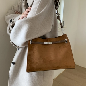 Detail view of brown suede tote bag featuring silver metal turn-lock and leather straps