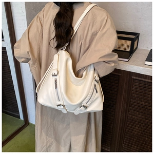 Detail of off-white oversized faux leather tote bag showing soft texture and zip accents