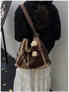 Detailed view of canvas tote bag with brown leather pockets and cute plush bear charm