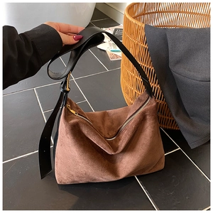 Detail of brown suede hobo bag with black leather strap and golden zipper hardware