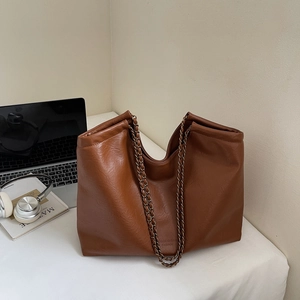 Brown textured PU tote bag detail with vintage chain strap and logo on modern office desk