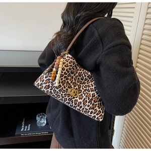 Detail of leopard print shoulder bag with gold metal clasp and colorful wood bead charm