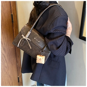 Détail d'un sac à bandoulière marron rétro avec poignée tressée et charm peluche