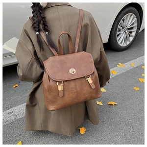 Outdoor shot of a vintage brown leather backpack featuring a golden twist lock closure