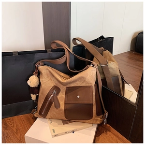 Detailed macro view of large canvas tote bag with brown leather pockets and teddy bear charm