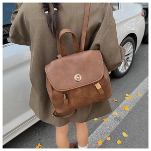 Detail of a brown vintage PU leather backpack with metallic turn-lock and adjustable straps