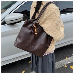 Détail du sac cabas vintage marron foncé avec logo embossé et breloque en perles de bois