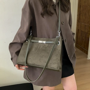 Detail of vintage dark green frosted leather tote with metallic twist lock and strap