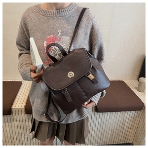 Detail of vintage dark brown PU leather backpack with gold clasp on a model