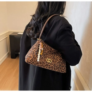 Detail of leopard print suede shoulder bag with gold hardware and beaded tassel charm